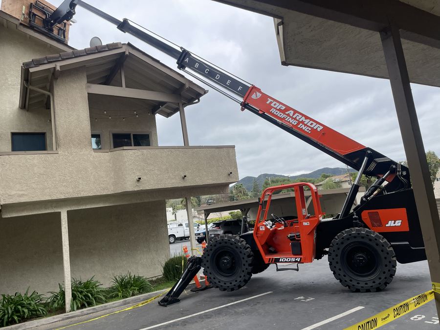 Telehandler boom extended over a two-story building